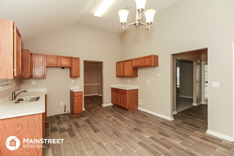 a kitchen with wood flooring and wooden cabinets and a sink