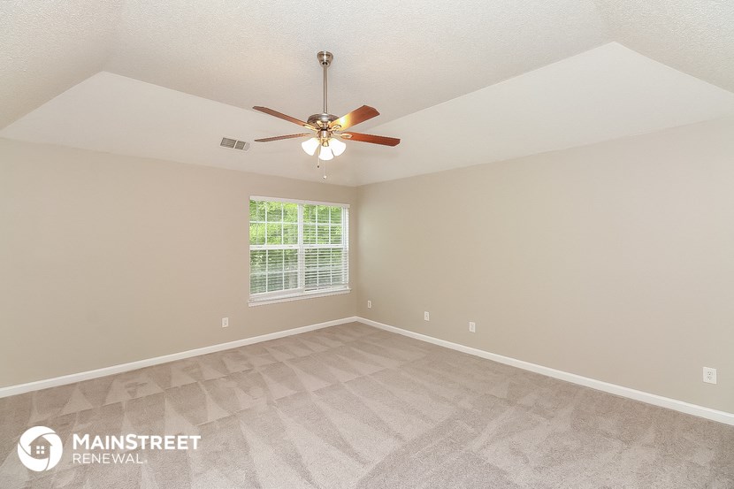 the spacious living room with ceiling fan and vinyl flooring