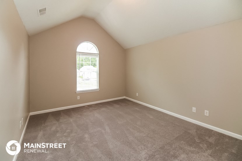 the spacious living room with carpeting and a large window