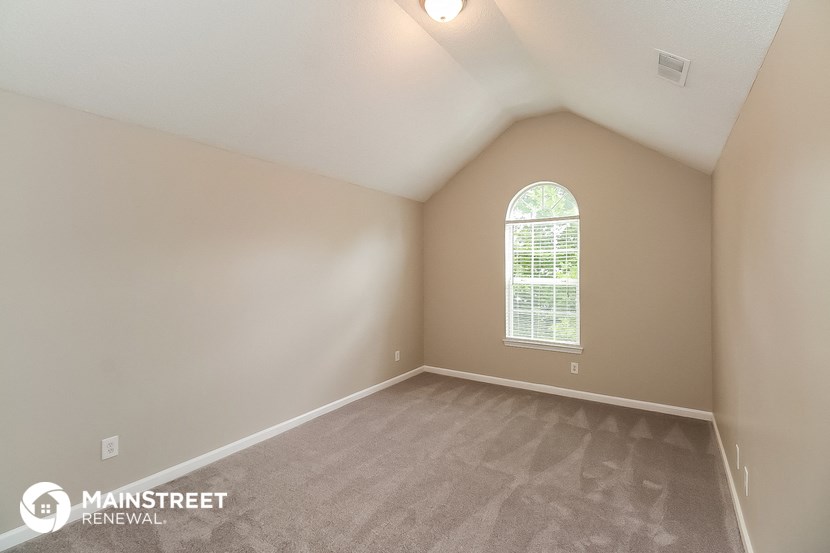 the upstairs bedroom with carpeting and a large window