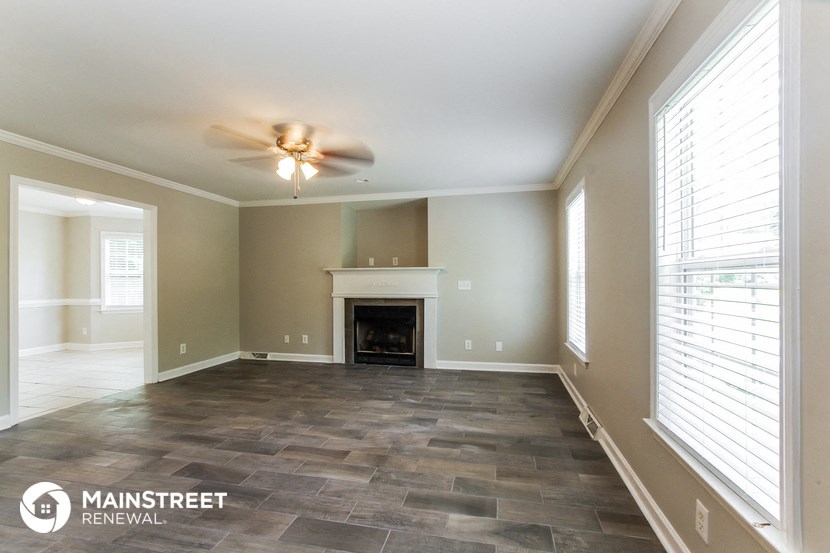 an empty living room with a ceiling fan and a fireplace