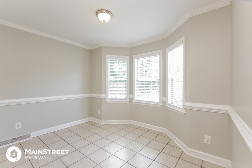 an empty dining room with three windows and a tiled floor