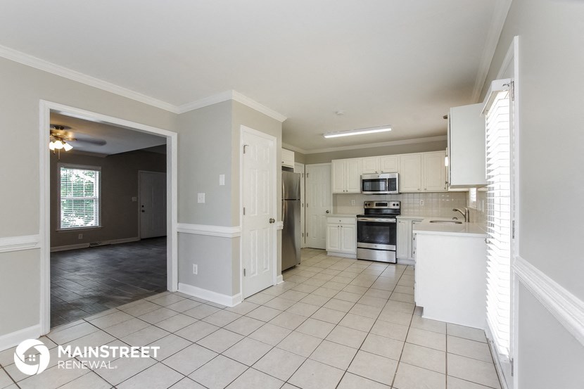 a large kitchen with white cabinets and a white tile floor