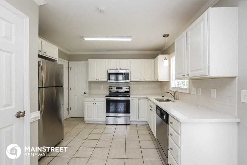 a large kitchen with white cabinets and stainless steel appliances