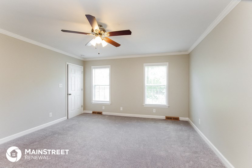 the master bedroom is spacious and clean with a ceiling fan