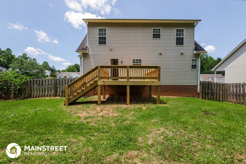 a backyard with a deck and a white house