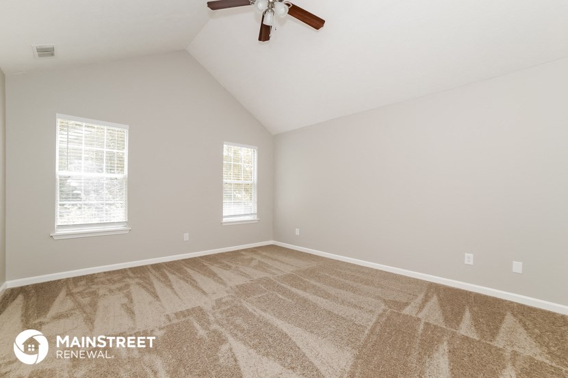 the living room of a home with carpet and a ceiling fan
