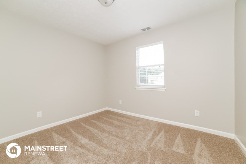 the upstairs bedroom with carpet and a window