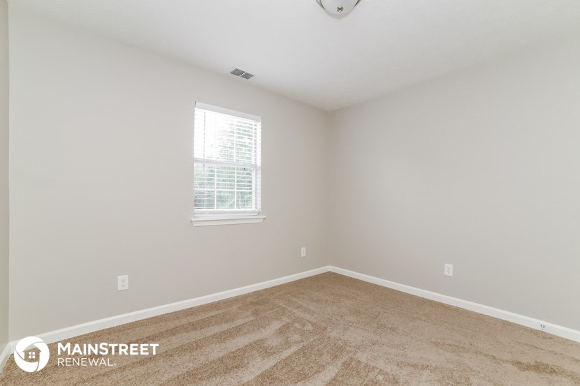 the spacious living room with carpeting and a window