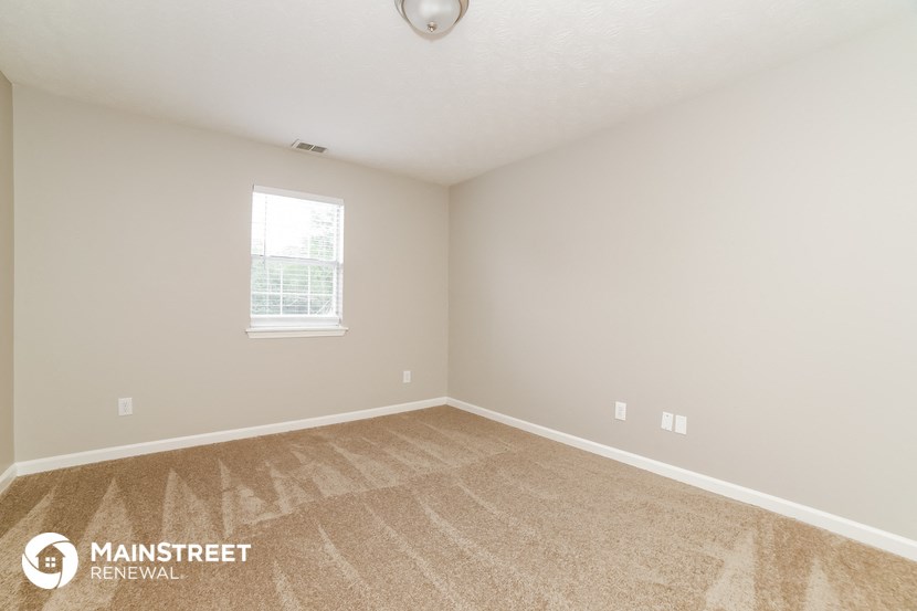the spacious living room with carpeting and a window