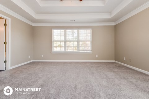 the spacious living room of a home with carpet and a window