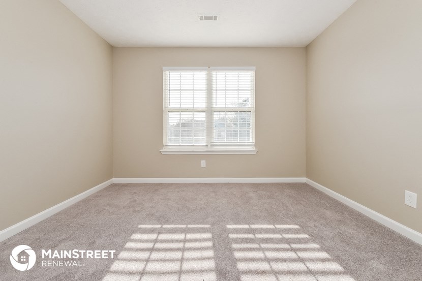 an empty room with a window and a carpeted floor
