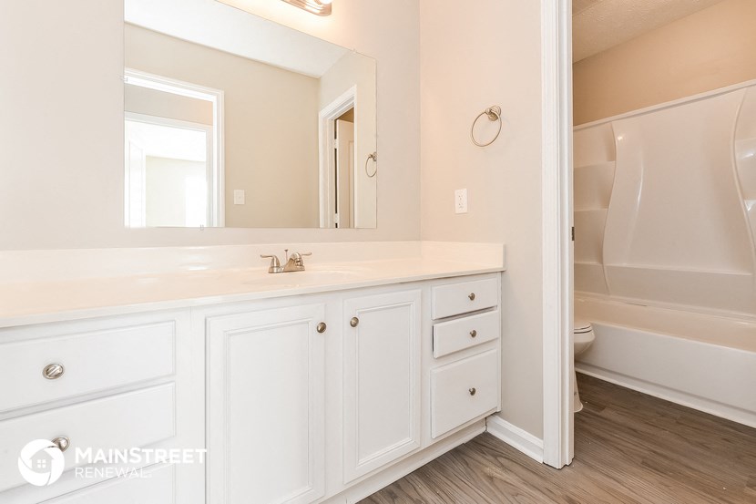 a bathroom with white cabinets and a sink and a mirror