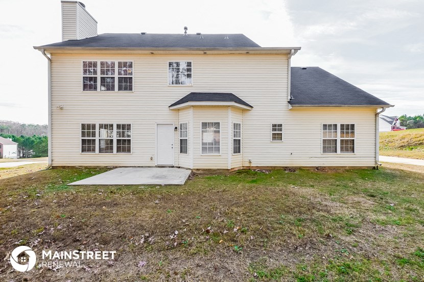 the back of a white house with a yard and a ramp