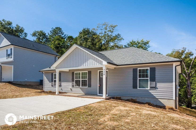 a small white house with a sidewalk in front of it
