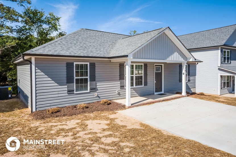 a blue house with a porch and a driveway