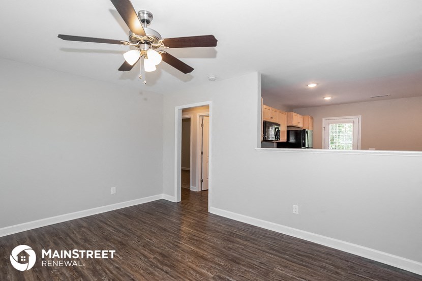 the living room and kitchen of a renovated house with a ceiling fan