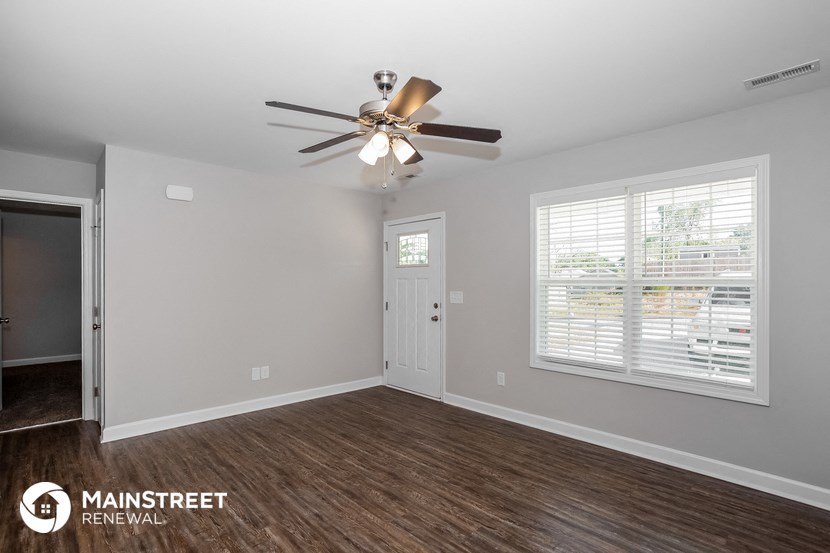 the living room of a home with a ceiling fan and a door