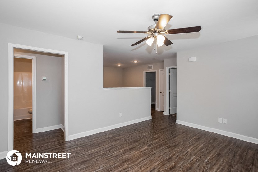 the living room and dining room of an apartment with a ceiling fan