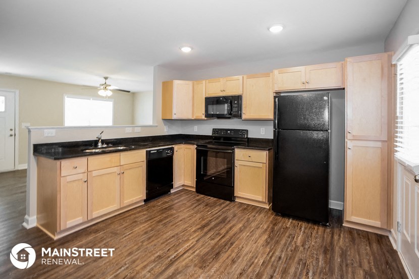 a kitchen with black appliances and wood flooring