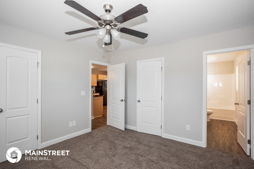 a living room with a ceiling fan and a door to a bathroom