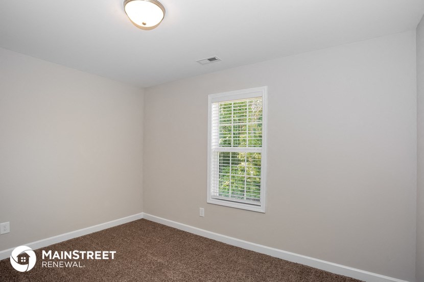 the upstairs bedroom with carpeted flooring and a window
