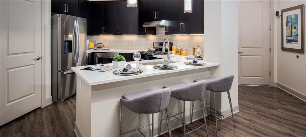 a kitchen with a counter with three chairs