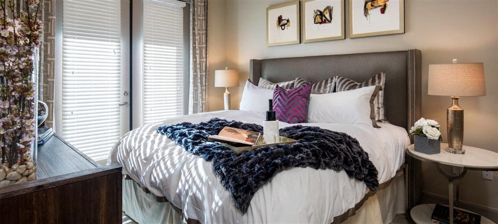 a bedroom with a bed and a bottle of wine on it