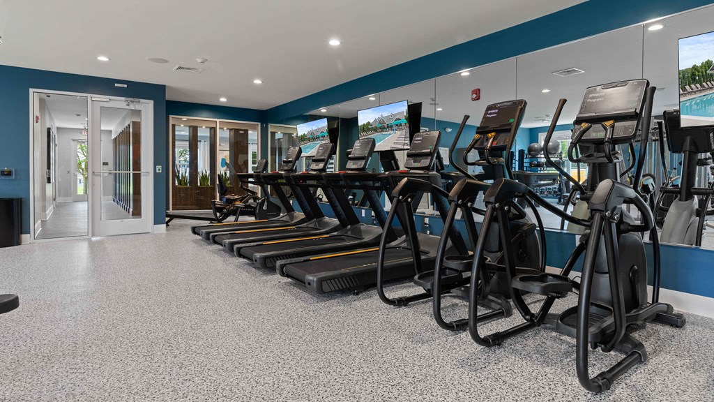 a row of treadmills in a gym with glass doors