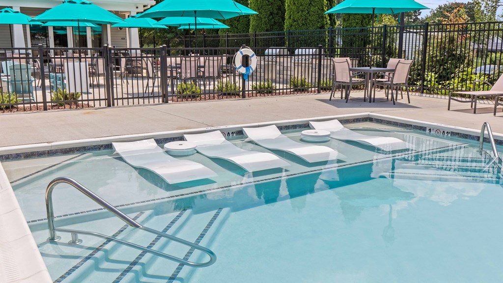 a swimming pool with chairs and umbrellas in front of a resort style pool