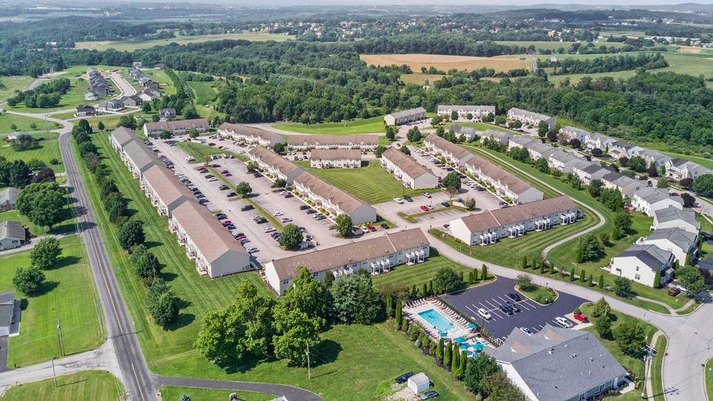 an aerial view of a parking lot with houses and trees