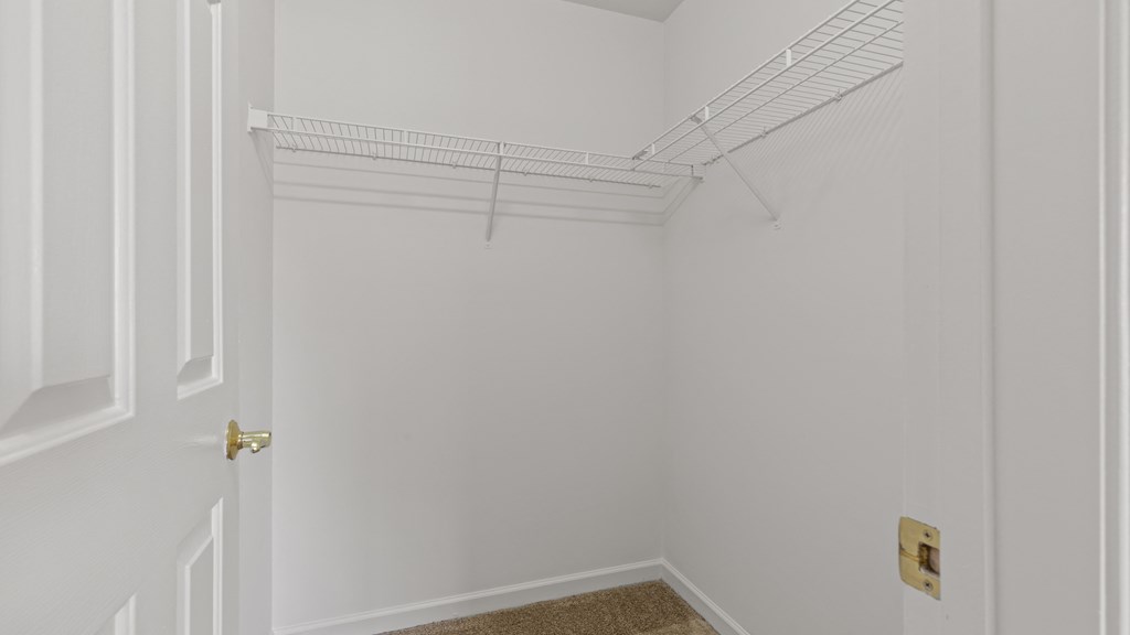 a white closet with a white door and a white shelf on the wall