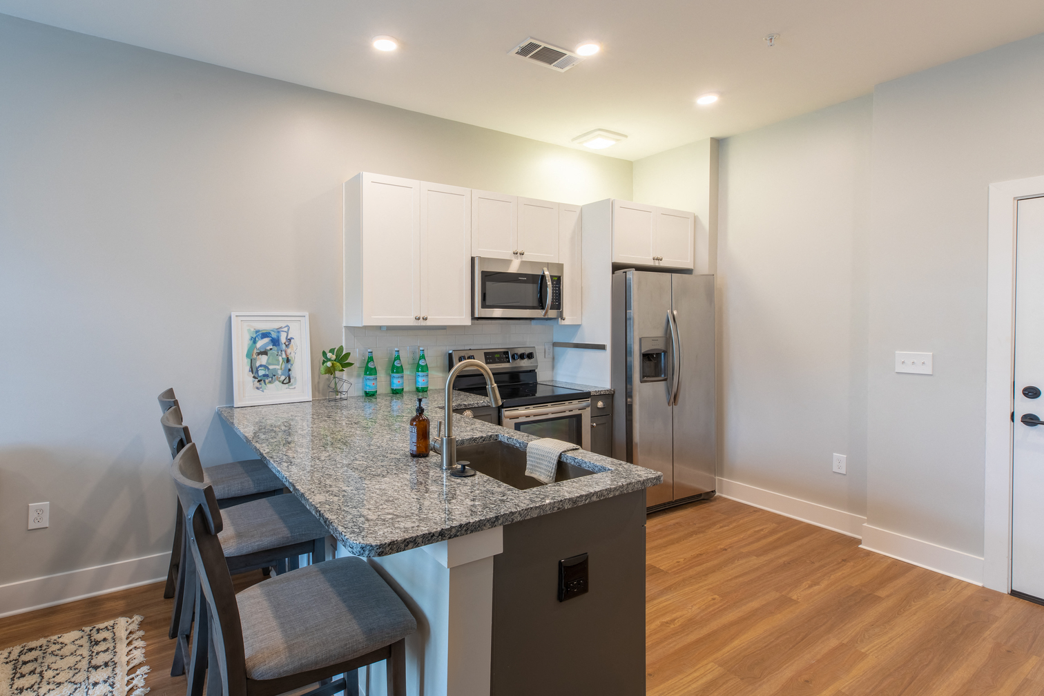 a kitchen with a granite counter top and a stainless steel refrigerator