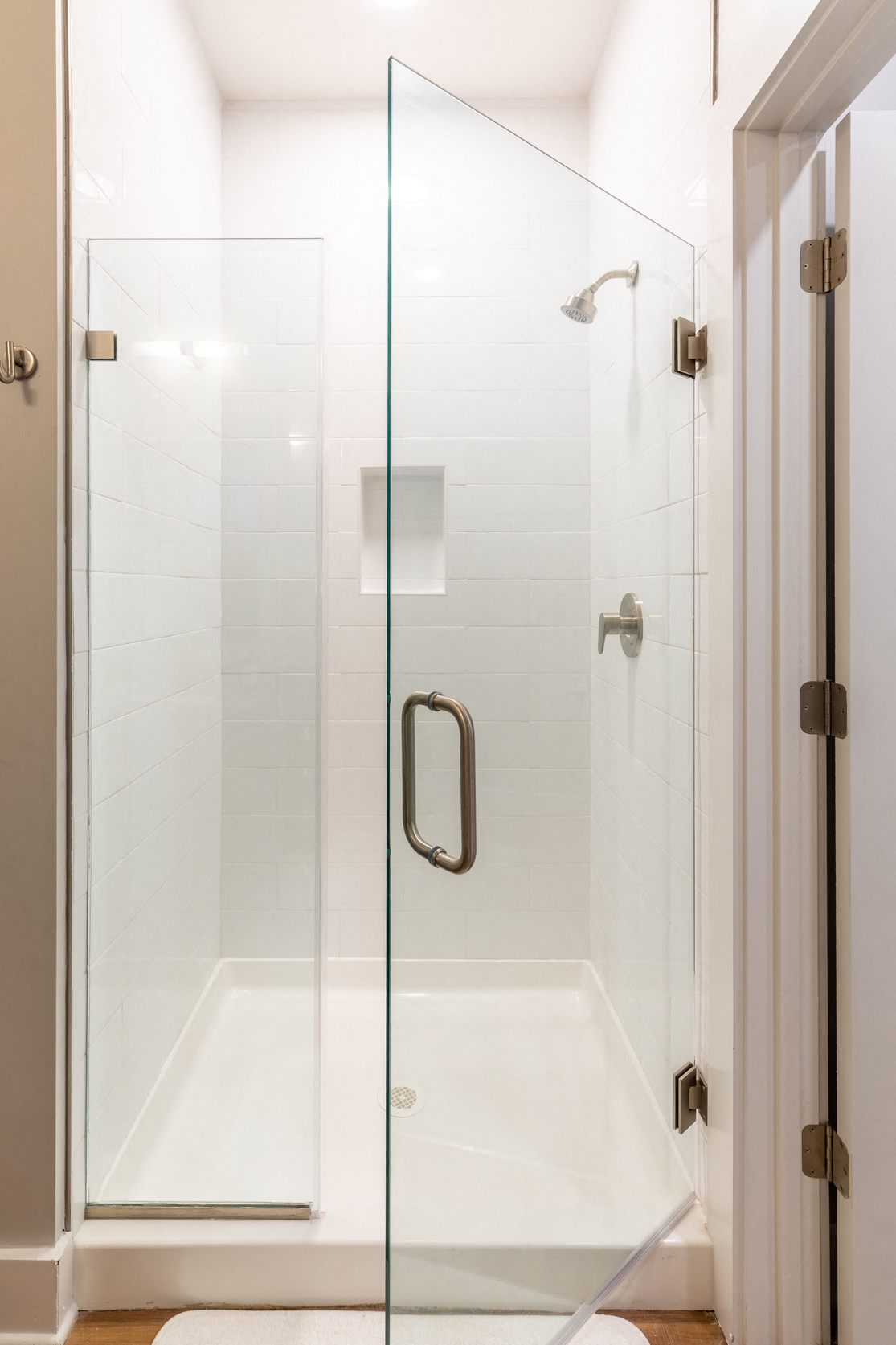 a shower with a glass door in a white bathroom