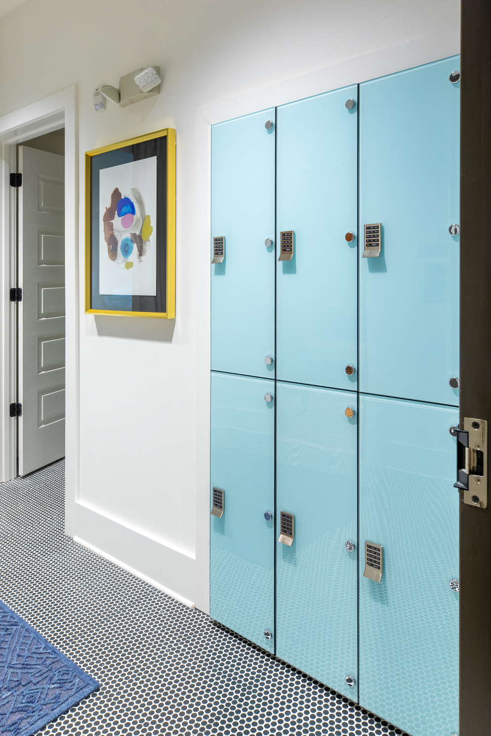 a hallway with blue lockers and a painting on the wall