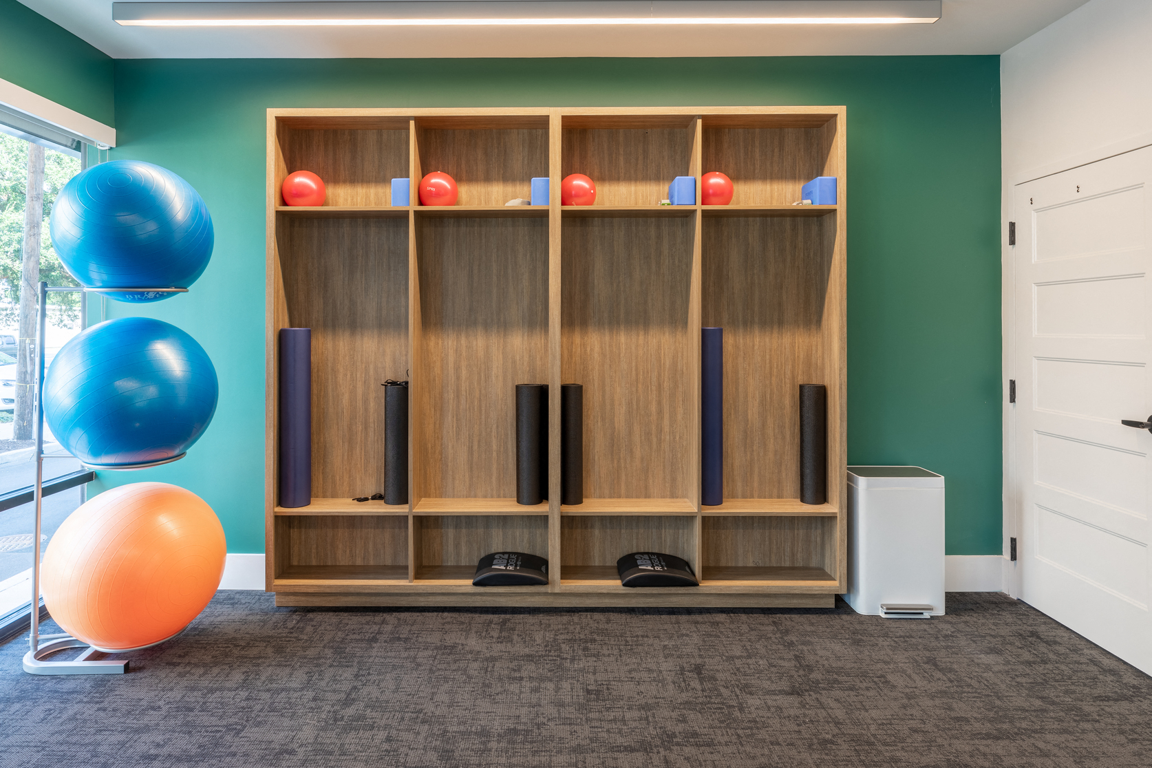 a fitness room with a wooden shelving unit and an orange and blue ball