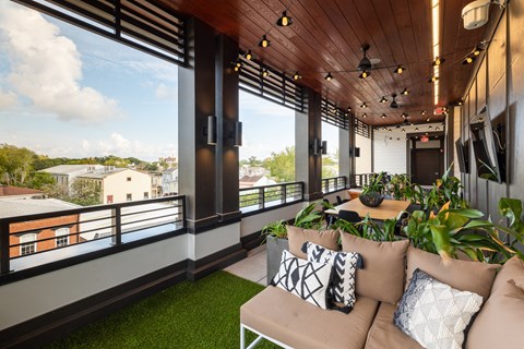 a living room with couches and plants on a balcony