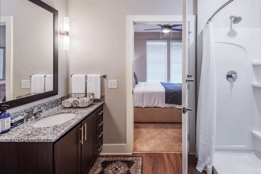 a bathroom with a sink and a shower and a bedroom