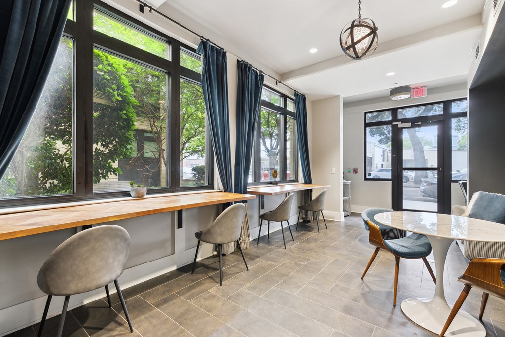 a dining area with tables and chairs and windows with blue curtains