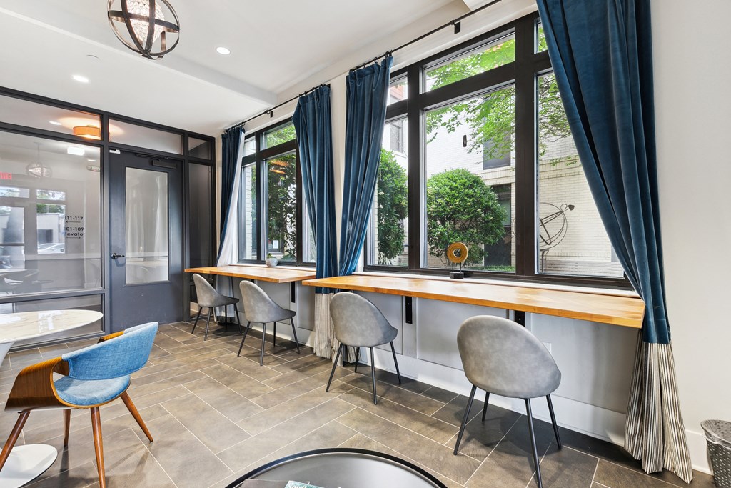a dining room with a table and chairs and windows with blue curtains
