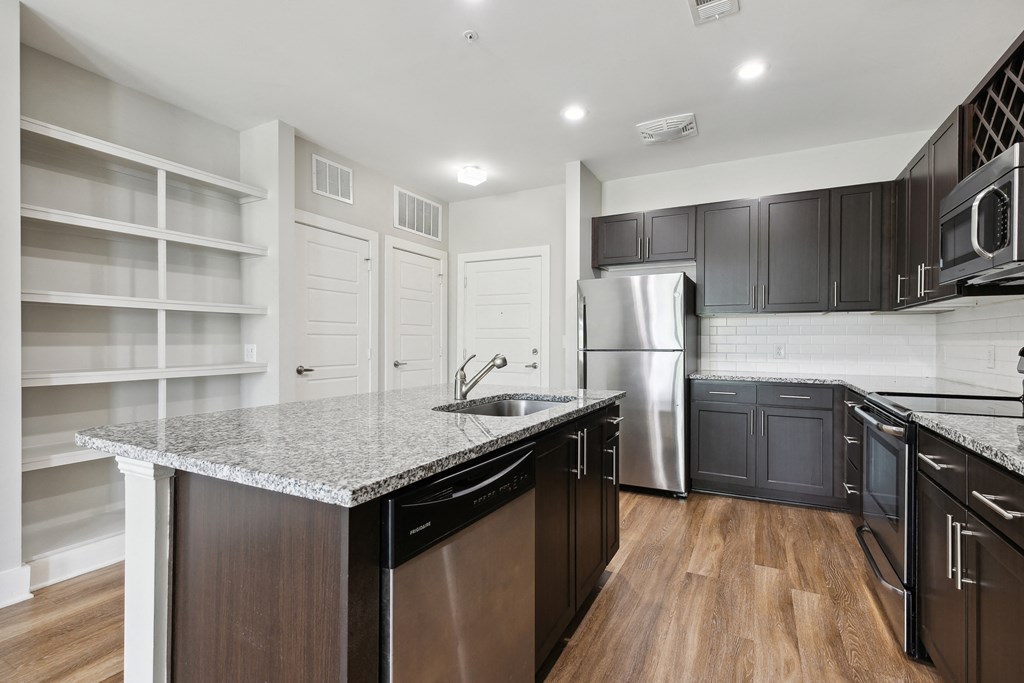 a kitchen with black cabinets and a marble counter top
