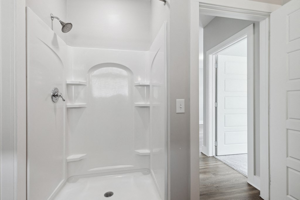 a white bathroom with a shower and a door