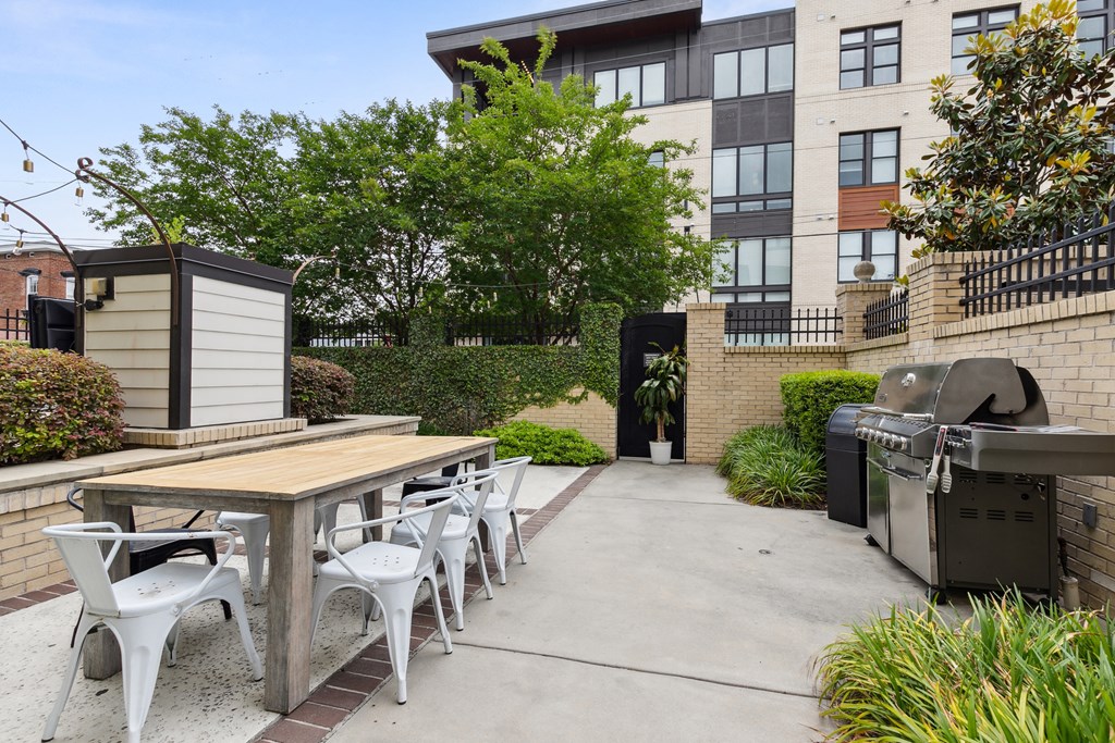 a patio with a table and chairs and a grill
