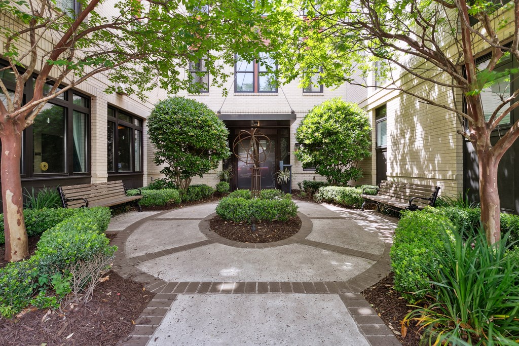 a courtyard with benches and trees in front of a house