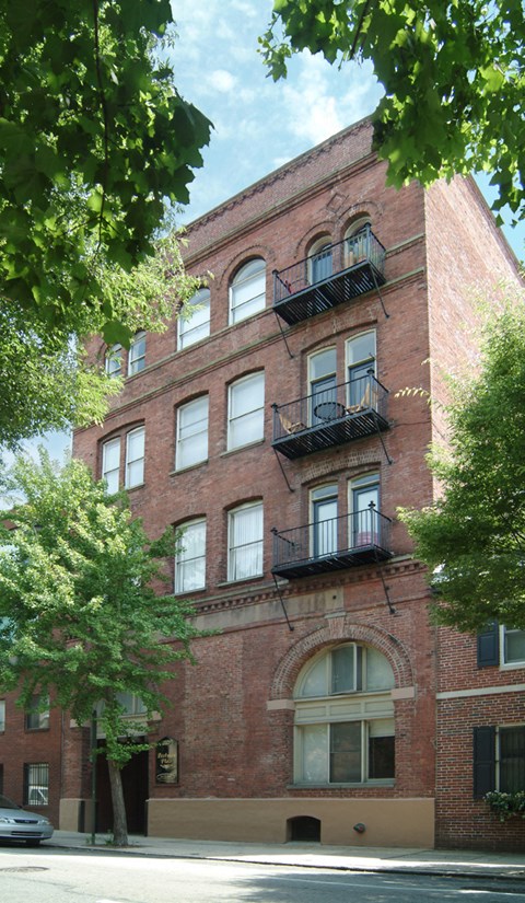 a red brick building with two balconies and trees