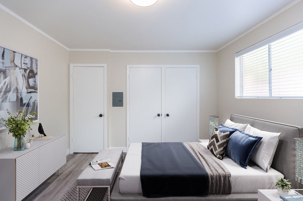 a bedroom with white walls and a bed with blue and white pillows