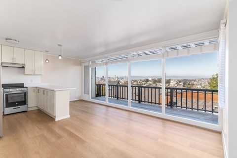 A kitchen with a stove top oven and a balcony with a railing.