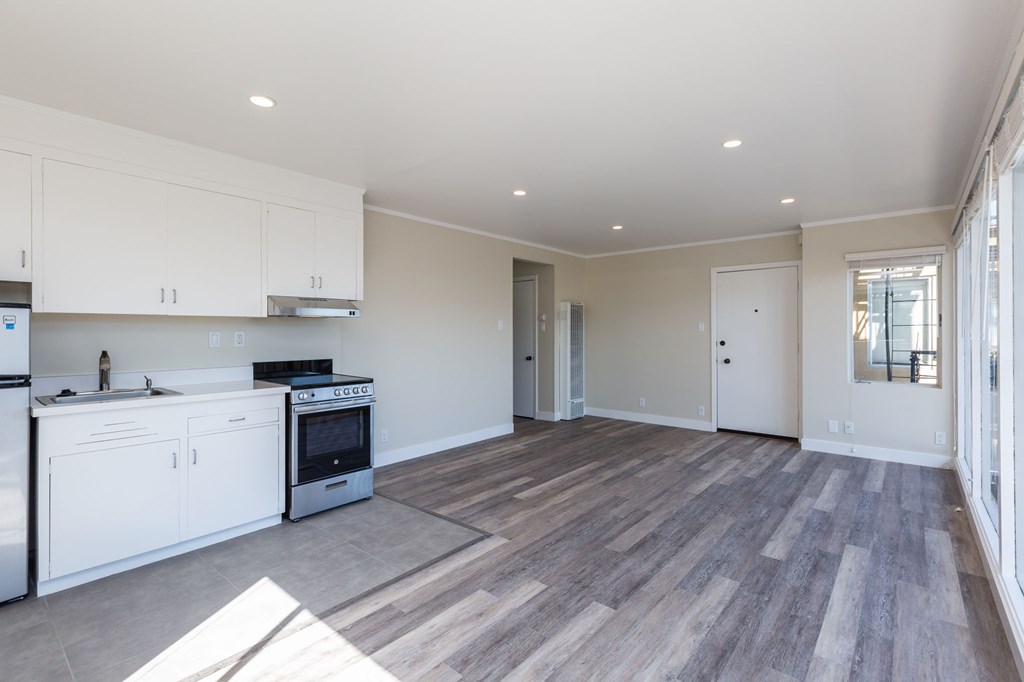 a kitchen and living room with white cabinets and wood floors