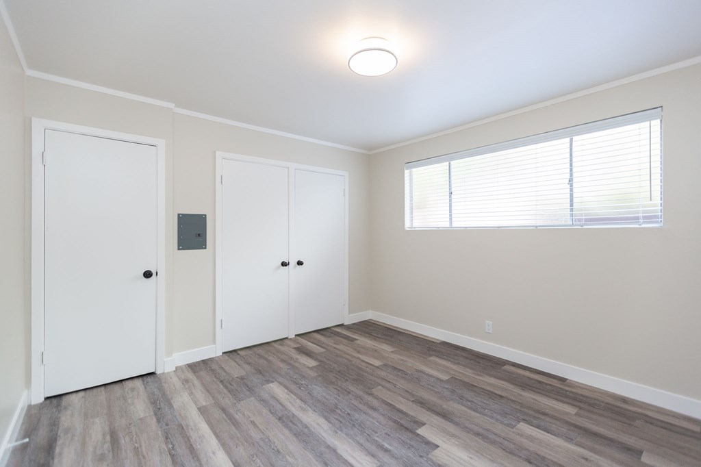 an empty room with white walls and wood floors and a window