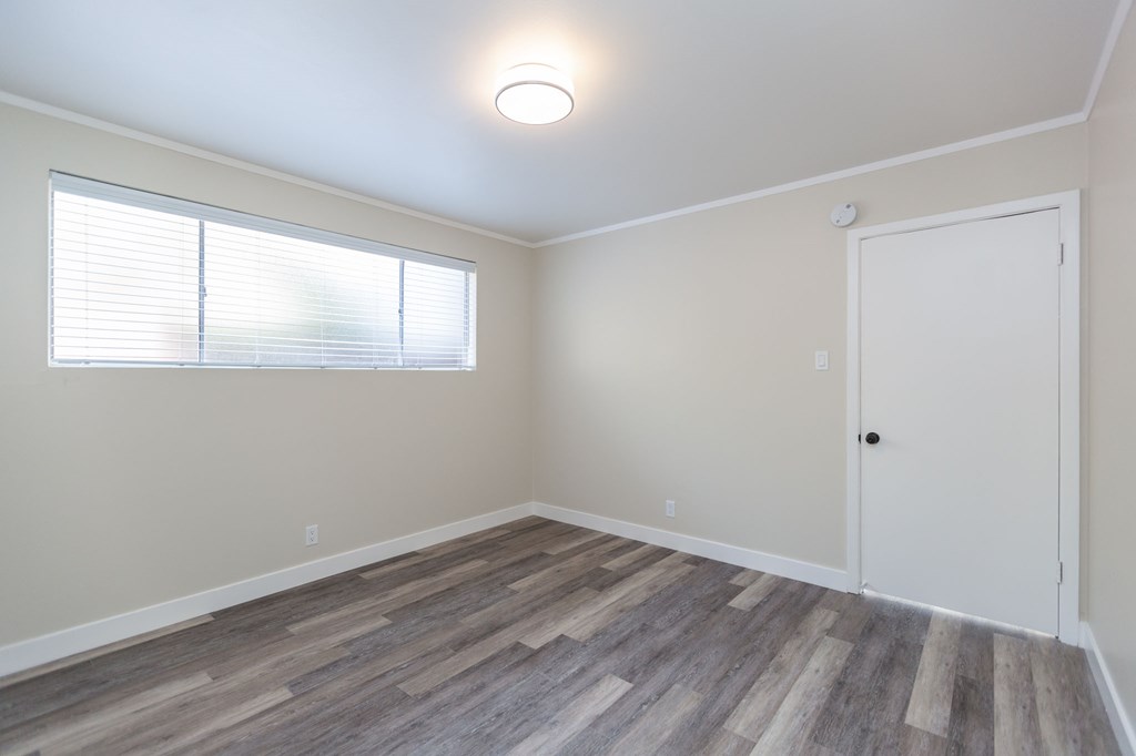an empty room with wood flooring and a white door and window